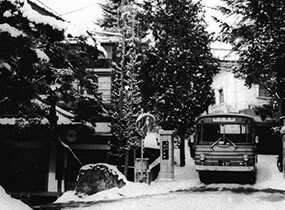 田村旅館の門を出発するバス